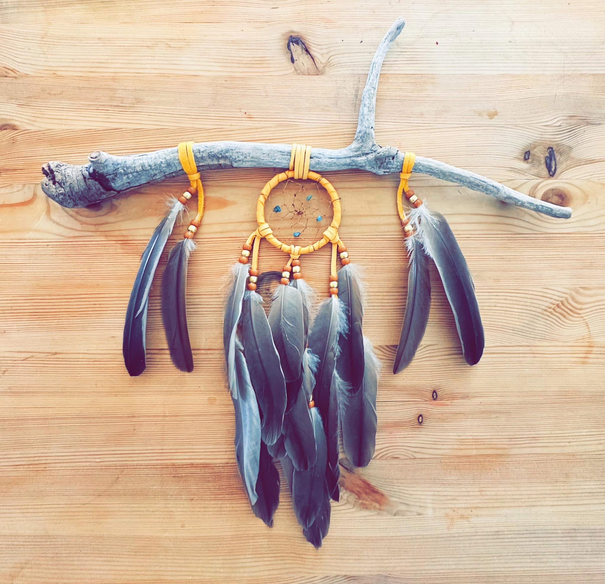 Œuvre murale avec plumes et message spirituel, réalisée en cuir d’orignal et matériaux naturels du Nitassinan.