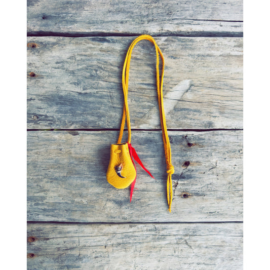 sac de medecine en cuir d’orignal avec griffe de loup sur planche de bois